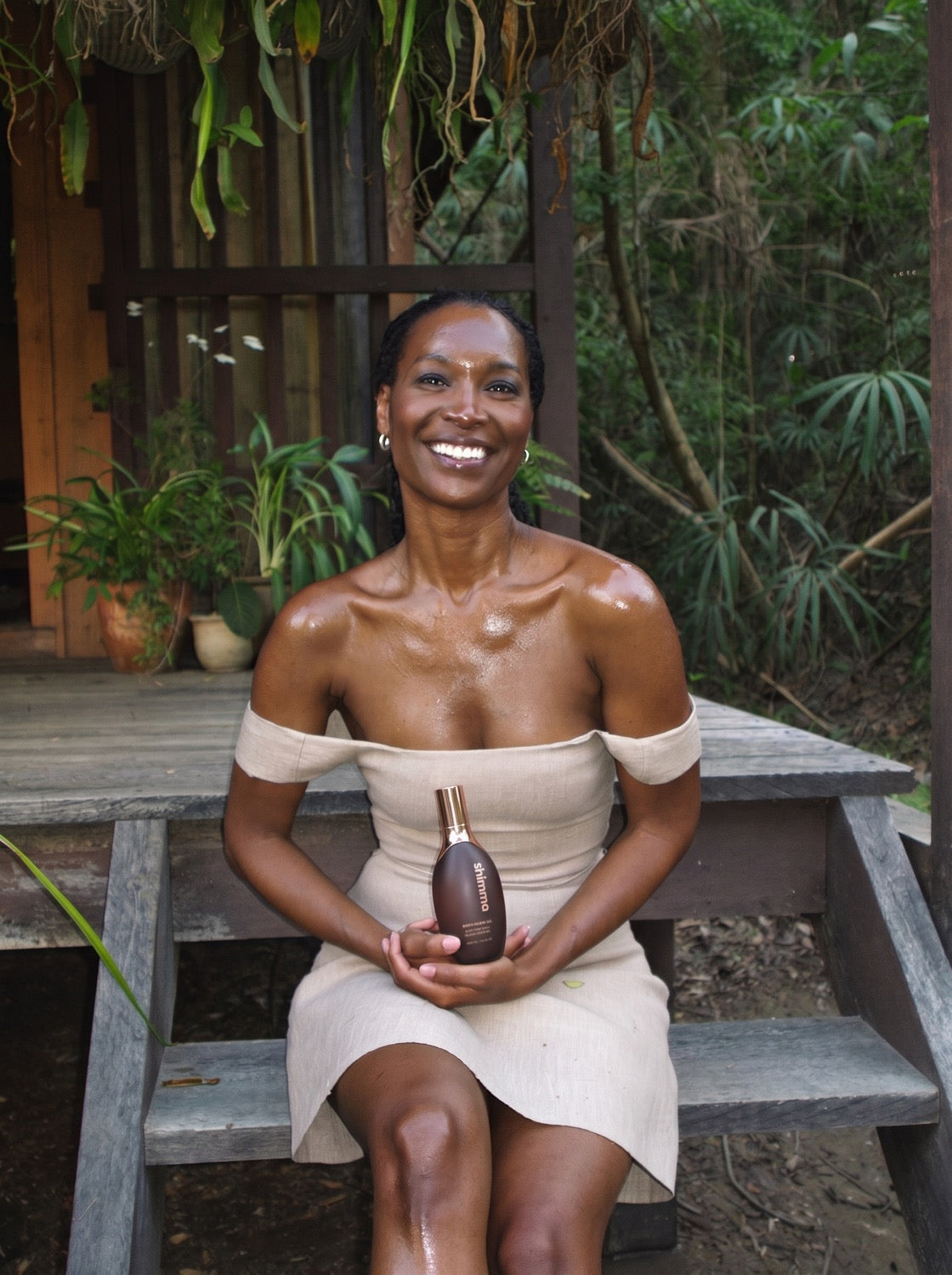 Caribbean woman glowing skin holding Shimma body oil